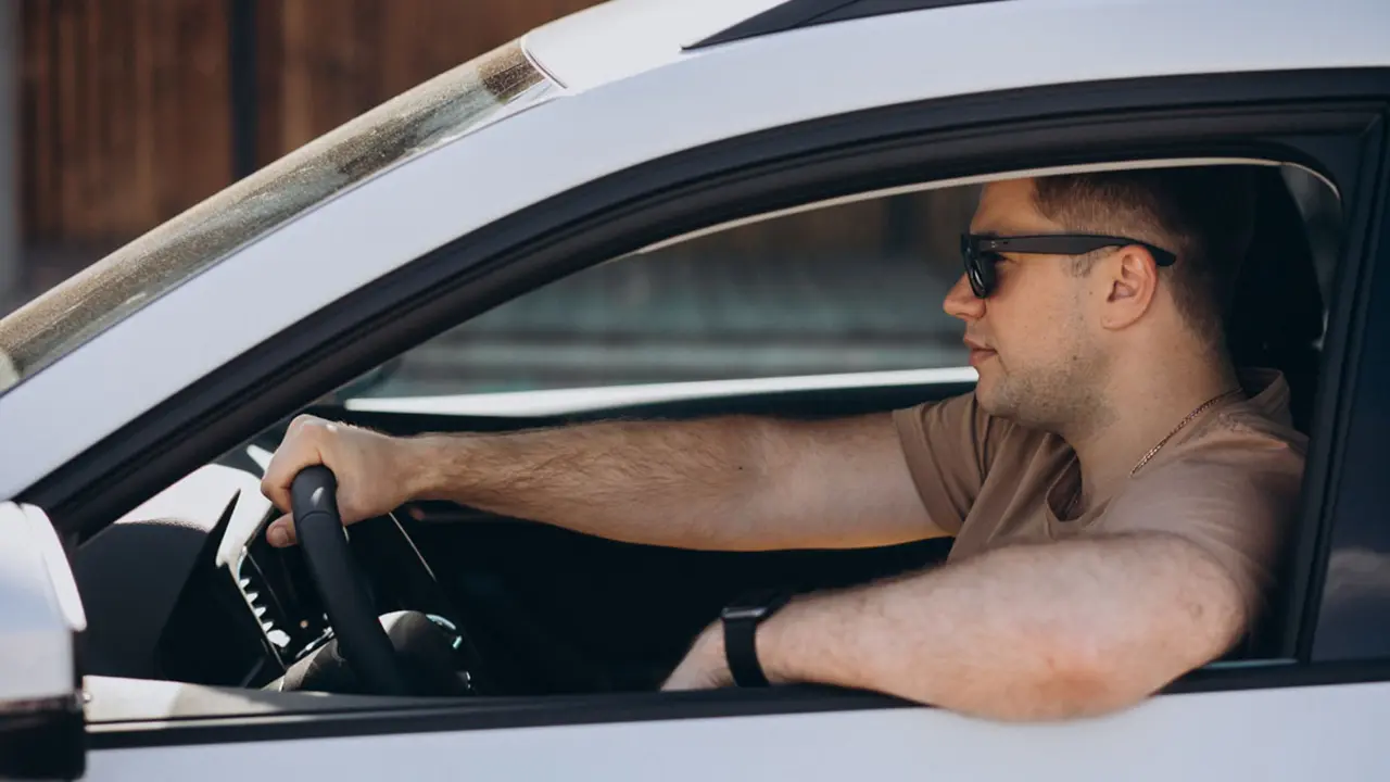 Conductor amb el colze per la finestra d&rsquo;un cotxe a l&rsquo;estiu