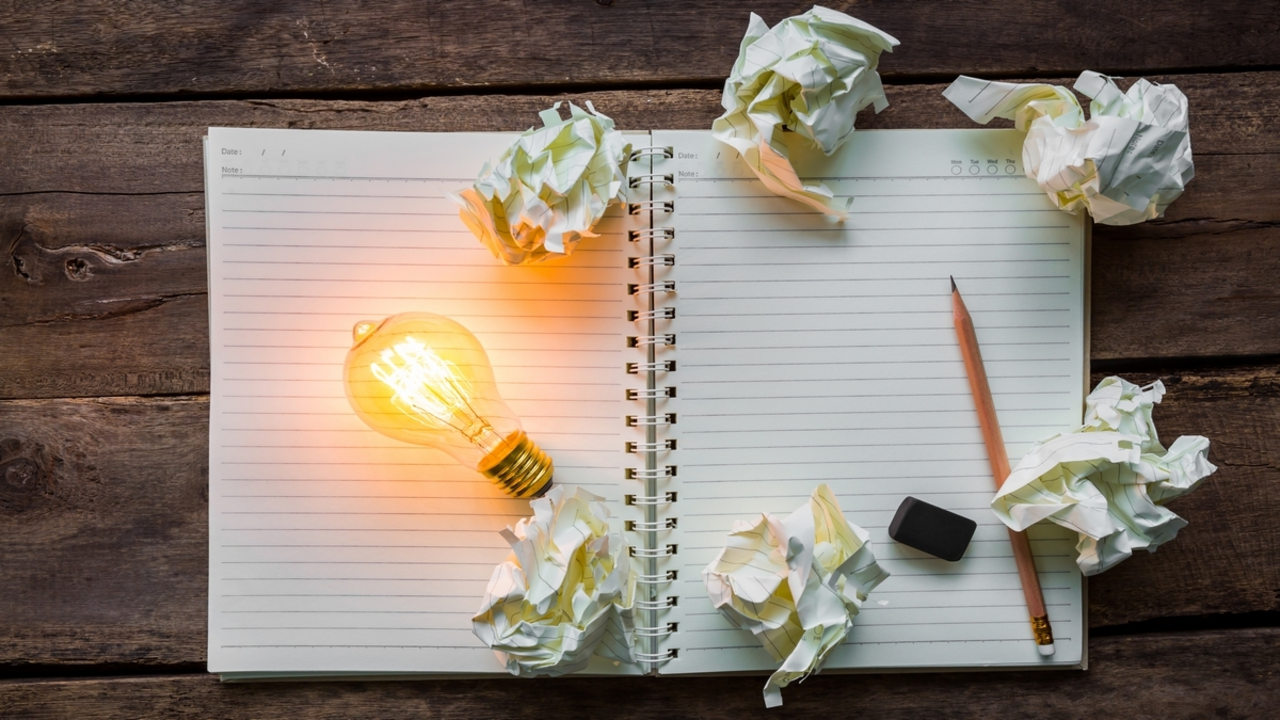 Note book and light bulb on wood table