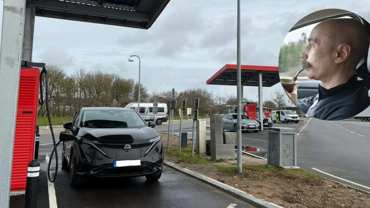 Vehicle el&egrave;ctric en c&agrave;rrega en una estaci&oacute; de rec&agrave;rrega a Catalunya amb paisatge urb&agrave; al fons