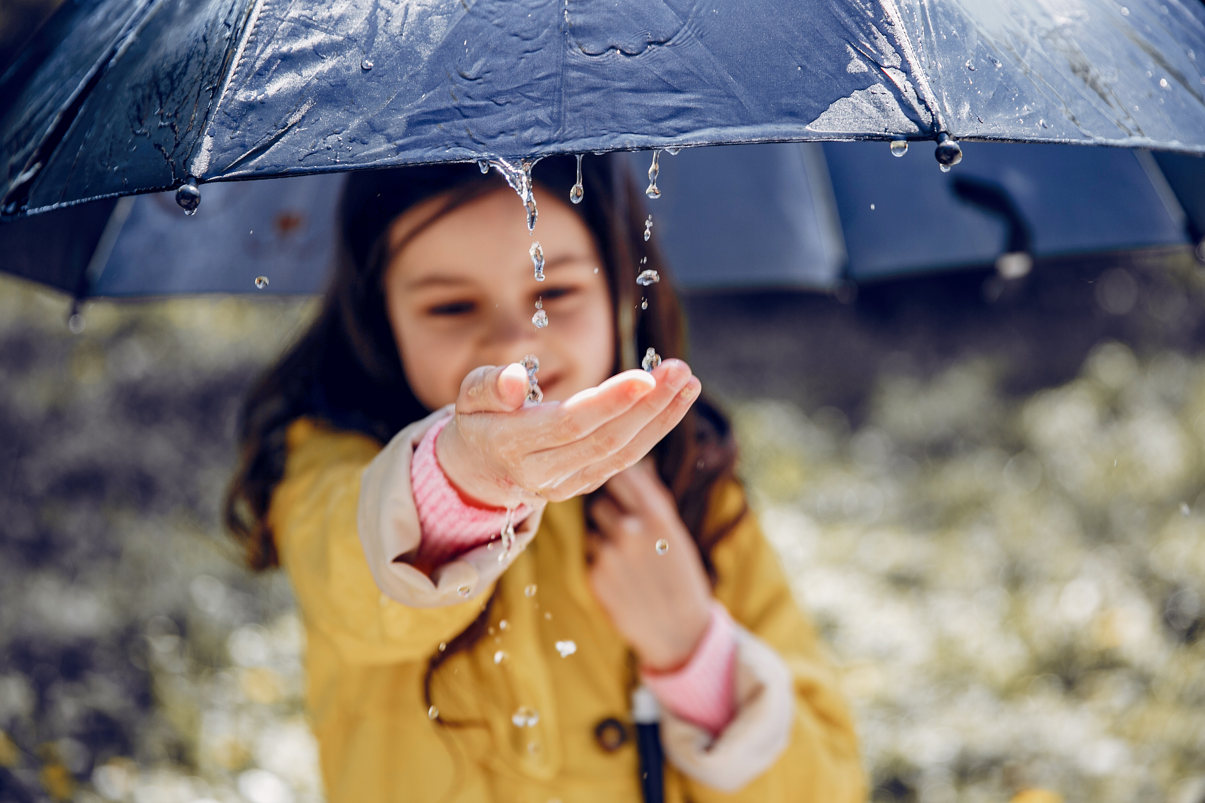 Little girl in a rain coat. Child playing in a park.